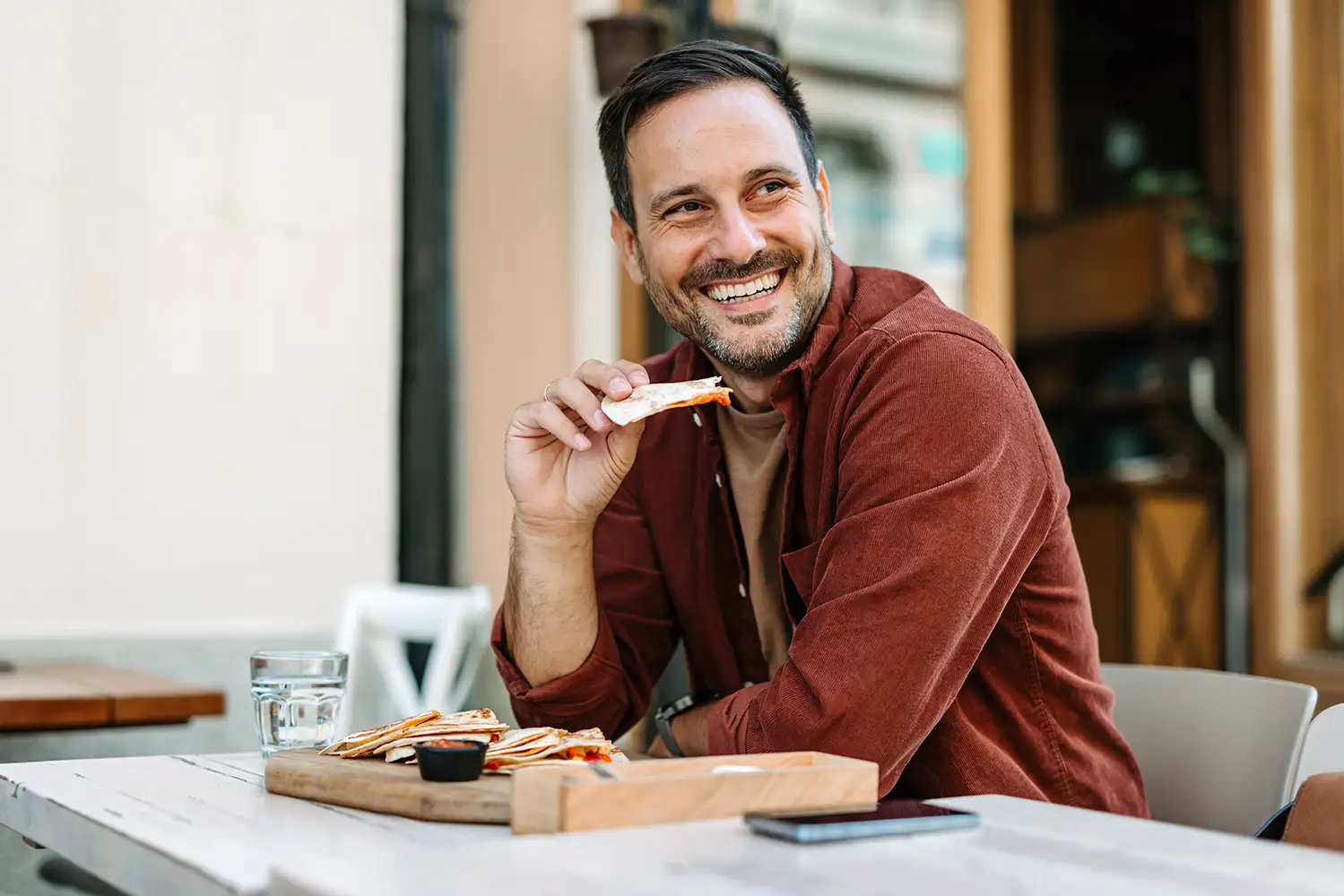 a man with a great smile at a restaurant eating a quesadilla