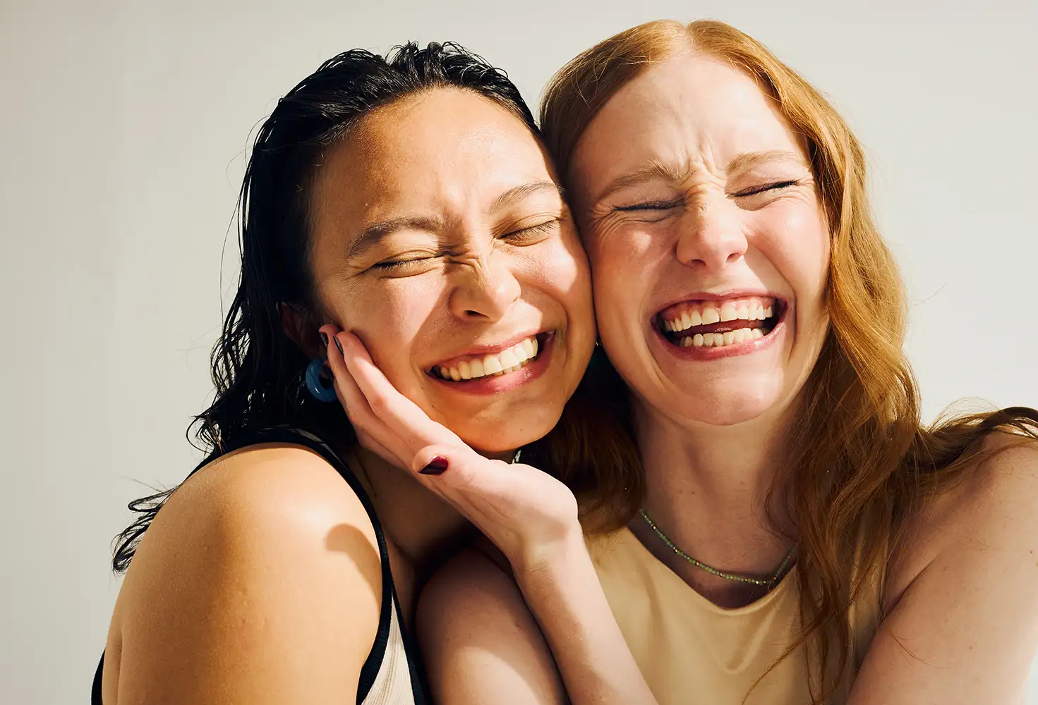 Two young adult women hugging and smiling at the camera